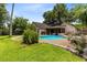 The spacious backyard has a sparkling blue pool, beautiful landscaping, and a well-manicured lawn at 7249 Abbey Ln, Winter Park, FL 32792