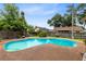 A turquoise inground pool and deck are surrounded by green grass, landscaping, and a wood fence at 7249 Abbey Ln, Winter Park, FL 32792