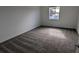 An empty bedroom offers neutral tones with plush gray carpeting and natural light from the window at 7612 Danube Rd, Kissimmee, FL 34746