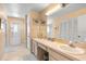 Well-lit bathroom featuring double sinks, tile floors, mirrored cabinets, and a shower with glass door at 7760 Indian Ridge N Trl, Kissimmee, FL 34747