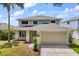 Charming two-story home featuring a well-manicured lawn and a two-car garage with palm tree at 8522 Blue Horizon Ct, Kissimmee, FL 34747