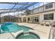 View of screened in pool, jacuzzi, and patio with seating from backyard of home at 8522 Blue Horizon Ct, Kissimmee, FL 34747