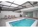A screened-in backyard with a private pool, lounge chairs, and outdoor dining area at 8944 Sydney Ave, Kissimmee, FL 34747