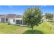 Spacious backyard with a lush green lawn and a large tree, plus a screened in patio at 1061 Suffragatte Cir, Haines City, FL 33844