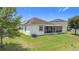 View of the home's backyard featuring a well-manicured lawn, air conditioning unit, and screened in patio at 1061 Suffragatte Cir, Haines City, FL 33844