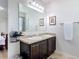 Well-lit bathroom with dual sinks, framed mirrors, and dark wood cabinets at 1061 Suffragatte Cir, Haines City, FL 33844