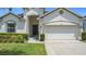 Charming single-Gathering home featuring a two-car garage, well-manicured landscaping and a walkway to the front door at 1061 Suffragatte Cir, Haines City, FL 33844