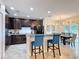 Modern kitchen featuring dark wood cabinetry, granite countertops, a breakfast bar, and a dining area at 1061 Suffragatte Cir, Haines City, FL 33844
