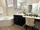 Well-lit bathroom featuring a soaking tub, vanity with black cabinets, and a separate makeup area at 1062 Rock Creek St, Apopka, FL 32712