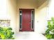 A red front door flanked by side lights is surrounded by lush green landscaping at 1062 Rock Creek St, Apopka, FL 32712
