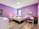 Bedroom with hardwood floors, a desk, shelves, bed with heart-patterned bedding and purple walls at 1086 Calla Lily Cv, Oviedo, FL 32766