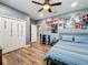 Bedroom features wood-look flooring, ceiling fan, closet, and light blue accent wall with posters at 1086 Calla Lily Cv, Oviedo, FL 32766