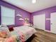 Bright, colorful bedroom features a heart-patterned bedspread, desk, and purple walls at 1086 Calla Lily Cv, Oviedo, FL 32766