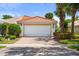 Inviting single-story home with a white garage door, red tile roof, and beautiful landscaping at 11863 Delfina Ln, Orlando, FL 32827