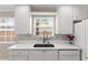 Close-up of kitchen sink with modern faucet, mosaic backsplash, and bright white cabinets with backyard views at 11863 Delfina Ln, Orlando, FL 32827