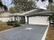 Charming single-story home with a gray driveway, a two-car garage, and landscaped front yard at 144 Costa Mesa Dr, Lady Lake, FL 32159