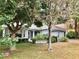 Charming single-story home with a landscaped front yard featuring mature trees and lush greenery at 144 Costa Mesa Dr, Lady Lake, FL 32159