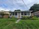 Exterior of a home featuring an enclosed porch, overgrown front lawn and weathered paint at 1620 Grand St, Orlando, FL 32805