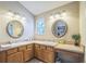 Bathroom with double sinks, matching vanities, a decorative mirror, and a bright window at 17567 Se 81St Parnassus Ct, The Villages, FL 32162
