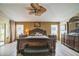 Well-lit main bedroom has a ceiling fan, wood-look flooring, and matching dark wood furniture at 17567 Se 81St Parnassus Ct, The Villages, FL 32162