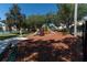 Community playground features swings, slides, and play structures on a mulch ground, bordered by trees and fencing at 2304 Silver Palm Dr # 304, Kissimmee, FL 34747