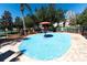 Community splash pad with a blue water surface, a central red umbrella, and palm trees at 2304 Silver Palm Dr # 304, Kissimmee, FL 34747