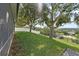 Lush, grassy backyard on a sloping lot with mature trees and a white fence offering privacy and a scenic view at 2950 Inca Ave, Clermont, FL 34715