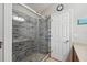 Modern walk-in shower with gray tile and river rock floor with a glass door at 2950 Inca Ave, Clermont, FL 34715