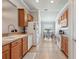 Galley kitchen with wooden cabinets, tile flooring, and modern appliances, leading to a dining area at 2950 Inca Ave, Clermont, FL 34715