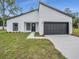 Modern home featuring a gray garage door, a simple landscaping design, and a freshly cut lawn at 357 Marion Oaks Pass, Ocala, FL 34473