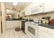Bright kitchen featuring white cabinets, appliances, and tile floors, with an open view to the dining area at 474 Windmeadows St # 0, Altamonte Springs, FL 32701