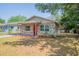 Delightful home with stone details, bright red door, manicured lawn, and carport at 4827 Elese St, Orlando, FL 32811