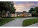 Stunning exterior of home with stone entryway, lush landscaping and circular driveway at sunset at 5025 Down Point Ln, Windermere, FL 34786