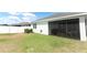 Rear view of home, with screened lanai and backyard featuring privacy fence under beautiful sunny skies at 5089 Meadow Song Dr, Okahumpka, FL 34762