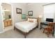 Comfortable bedroom showcasing neutral tones, a cozy bed, a desk, and natural light from the window at 5089 Meadow Song Dr, Okahumpka, FL 34762