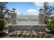 Stone community entrance sign surrounded by colorful flowers and landscaping, and clear blue sky at 5089 Meadow Song Dr, Okahumpka, FL 34762