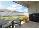 View of screened in patio with comfortable seating, table with flowers, and grill overlooking grassy backyard at 5089 Meadow Song Dr, Okahumpka, FL 34762