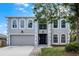 Charming two-story home showcasing arched windows, a gray facade, a well-manicured lawn, and mature trees at 520 Stonewall Ave, Haines City, FL 33844