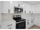 Close-up of a contemporary kitchen with sleek white cabinetry, quartz countertops, and stainless steel appliances at 520 Stonewall Ave, Haines City, FL 33844