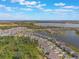 A serene aerial view displays a community bordering a large lake with homes dotted amidst trees and winding roads at 5226 Northern Flicker Dr, St Cloud, FL 34771
