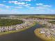 Aerial view of a community near a lake with a mix of residential homes and natural landscapes on a partly cloudy day at 5226 Northern Flicker Dr, St Cloud, FL 34771