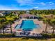 Aerial view of a community pool with surrounding lounge chairs, palm trees, and a nearby playground area at 5226 Northern Flicker Dr, St Cloud, FL 34771