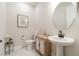 Charming powder room with unique sink, wood cabinet, white walls, and decorative artwork at 5226 Northern Flicker Dr, St Cloud, FL 34771