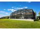 A spacious screened-in pool enclosure overlooks a well-maintained green lawn in a backyard setting with blue skies above at 5226 Northern Flicker Dr, St Cloud, FL 34771