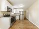 Clean kitchen featuring white cabinets, stainless steel appliances, granite countertops and wood-look floors at 5822 Flori Ln, Orlando, FL 32808