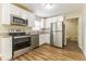 Bright kitchen with white cabinets, stainless steel appliances, granite countertops, and wood-look floors at 5822 Flori Ln, Orlando, FL 32808