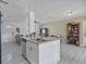 Bright kitchen featuring granite island, stainless appliances, gray flooring, and open living area at 601 Blackstone Ave, Deltona, FL 32725