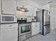 Modern kitchen with stainless steel appliances, white cabinetry, gray vinyl flooring, and granite countertops at 601 Blackstone Ave, Deltona, FL 32725