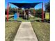 Community playground shaded by a blue awning featuring a colorful play structure and soft turf at 6512 Swissco Dr # 1428, Orlando, FL 32822