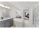 Bright bathroom featuring a soaking tub, dual vanities, and glass-enclosed shower with neutral tile at 7500 Alpine Butterfly Ln, Orlando, FL 32819